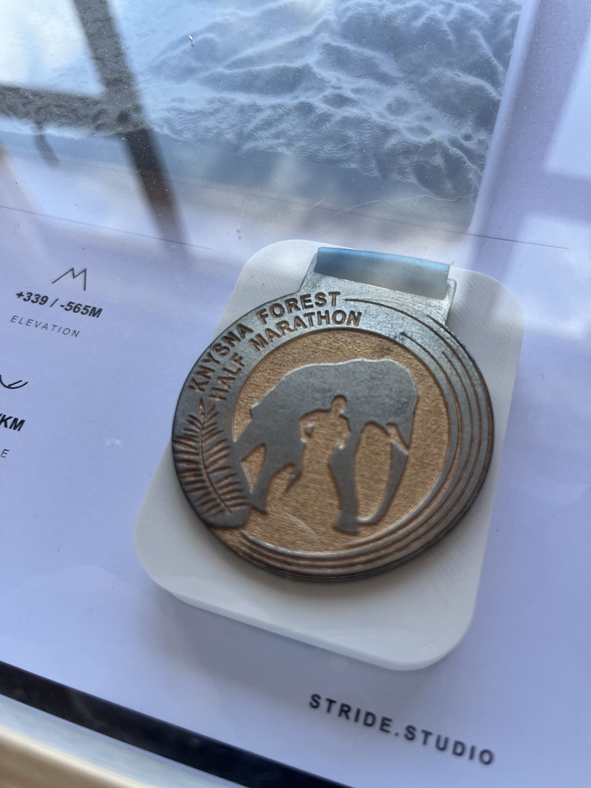 Close-up of a Knysna Forest Half Marathon finisher medal in its custom printed mount