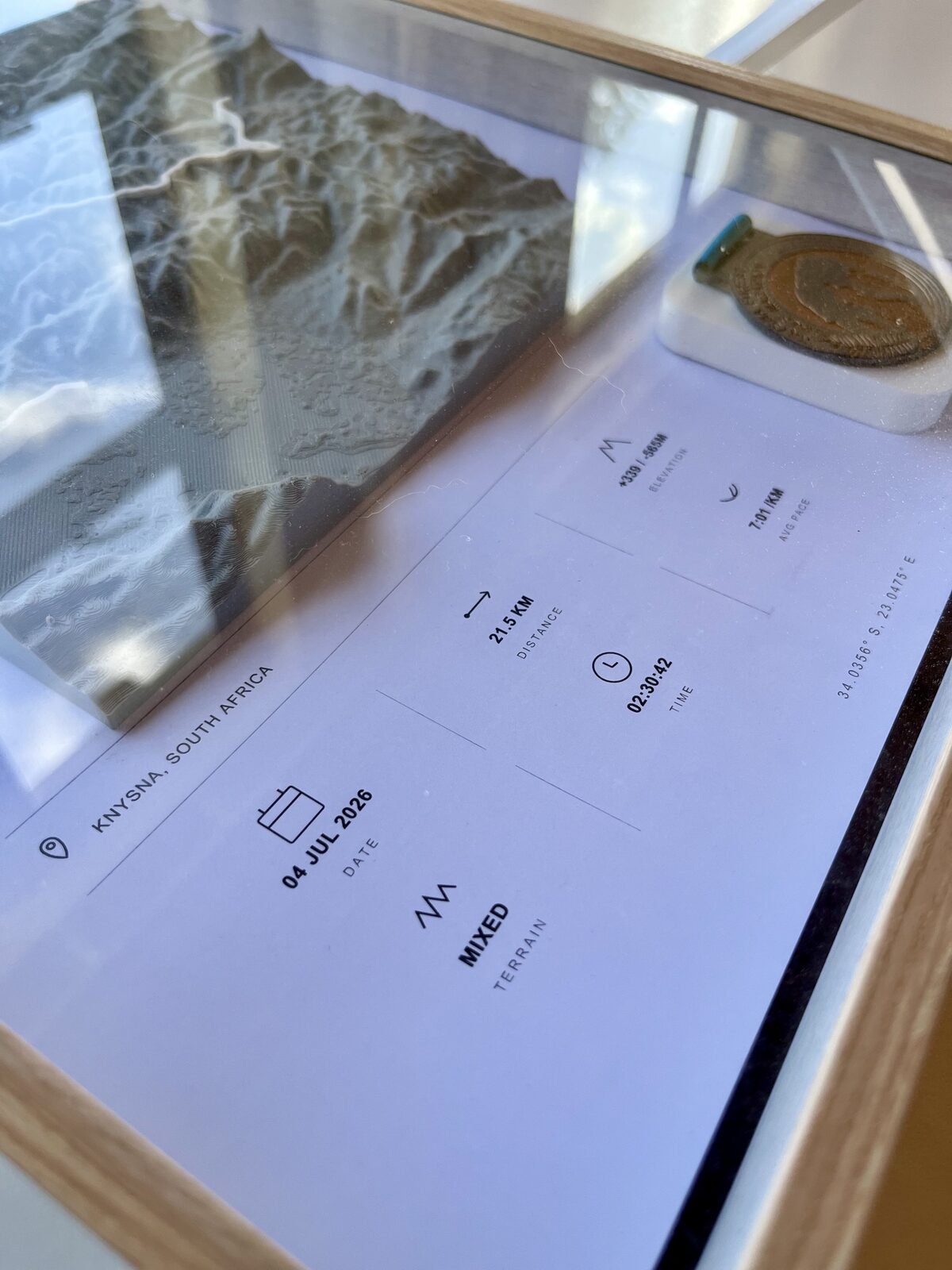 Angled view of a Stride Studio shadow box showing depth of the 3D printed terrain behind glass