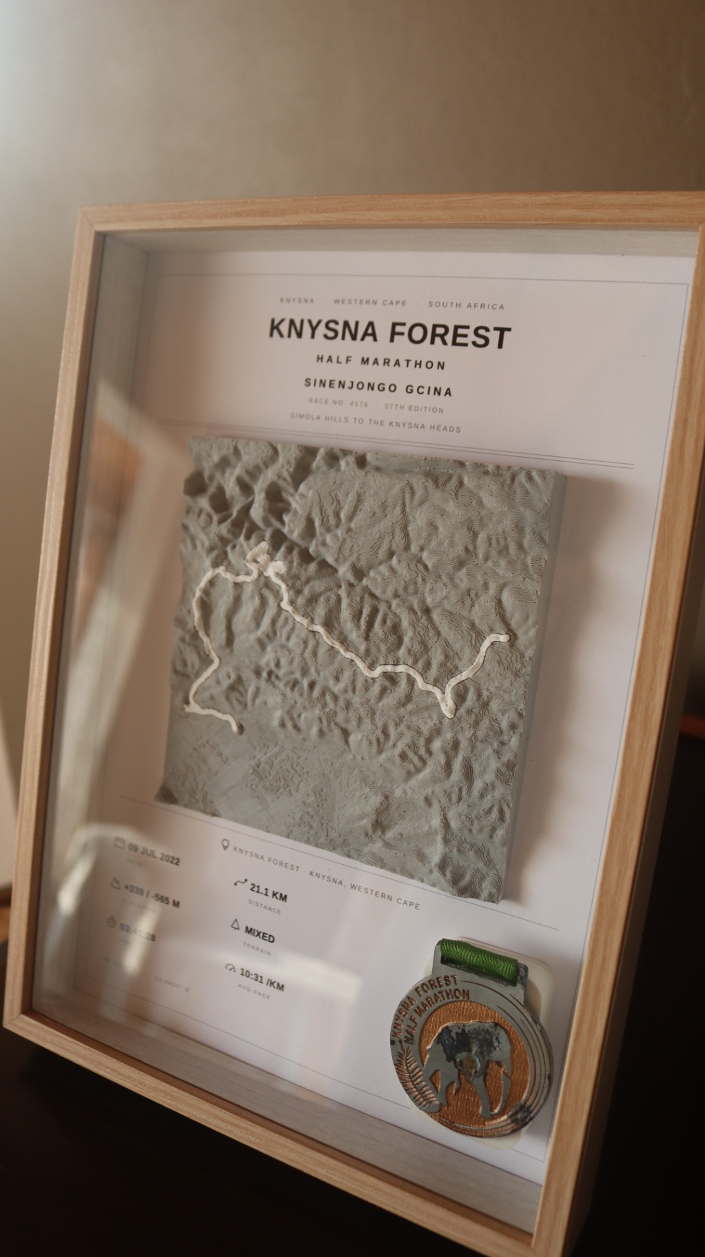 Complete framed Knysna Forest Half Marathon display with 3D terrain map, race stats and finisher medal in an oak frame