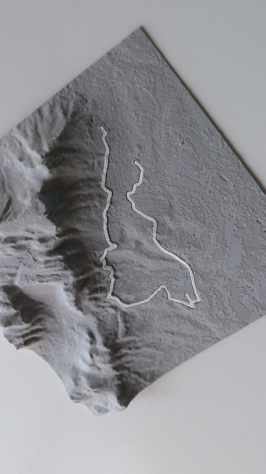 Square 3D relief map of a race route showing mountainous terrain with a raised white path winding through it